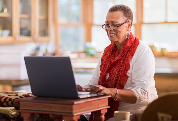Older mixed race woman using laptop in home office